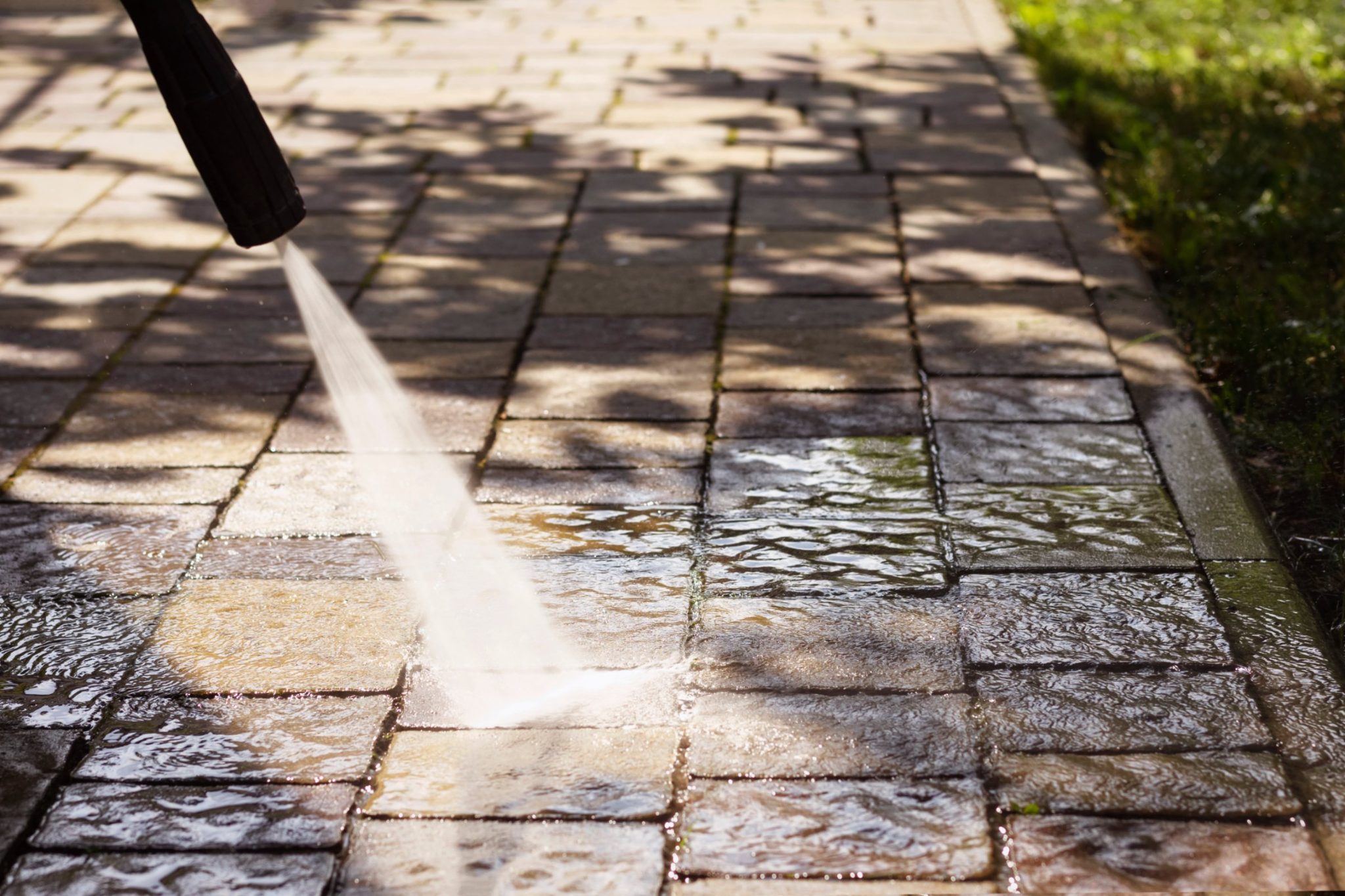 Pressure washing paver patio with white water stream from nozzle